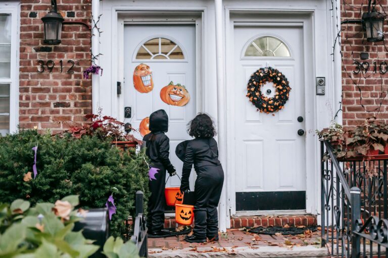 Halloween front porch decorated with glowing pumpkins, lanterns and a skeleton at dusk