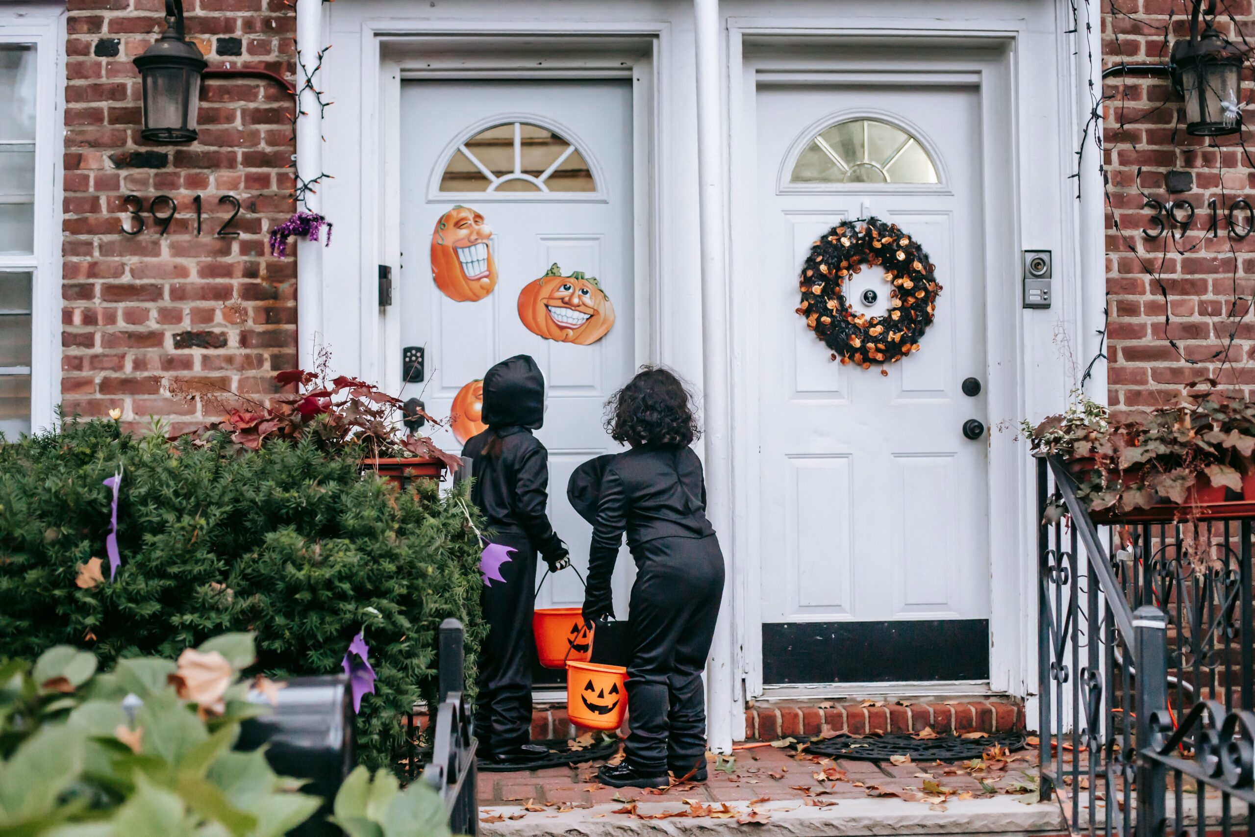 Halloween front porch decorated with glowing pumpkins, lanterns and a skeleton at dusk